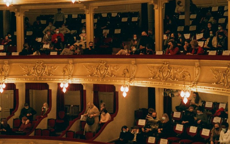Publikum iin der Oper, veranschaulicht die persönliche Beratung und Unterstützung, die 'Künstler für Künstler' bietet.